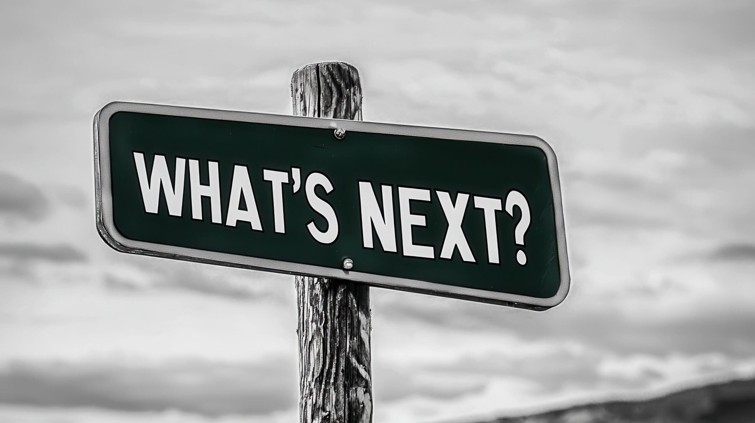 We Discover What's Next in AI Marketing Tools Street sign reading “What’s Next?” against a cloudy sky, representing future-focused marketing strategy and innovation.