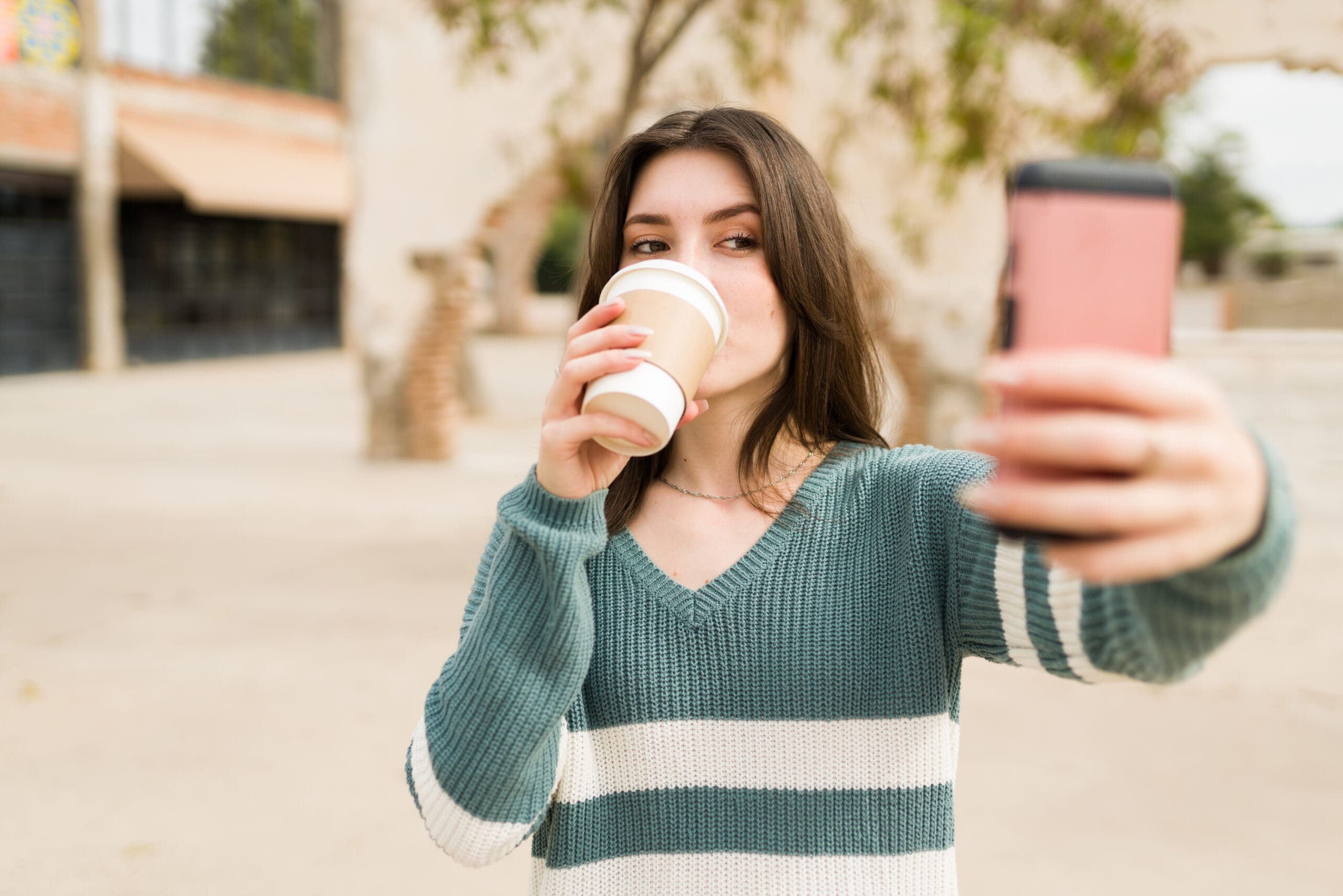 Retail Trends for Gen Z and Generation Alpha Retail trends for Gen Z represented by a young shopper taking a selfie with coffee outdoors.