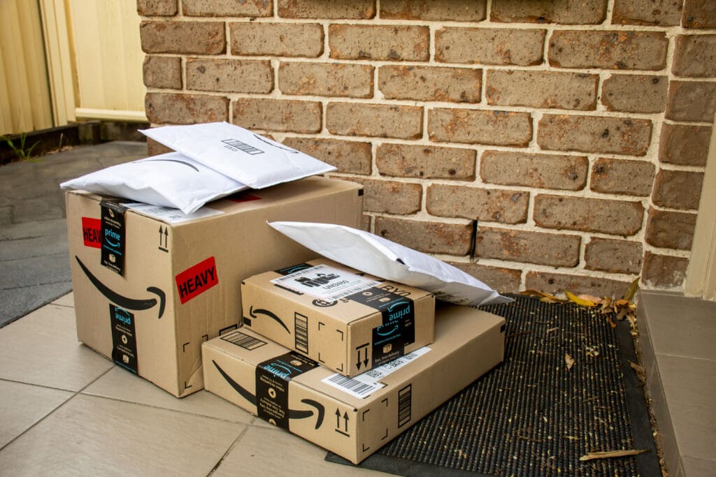 The Battle Between Local Retail and Online Shopping Giants Amazon packages delivered to a doorstep representing the rise of local retail and online shopping
