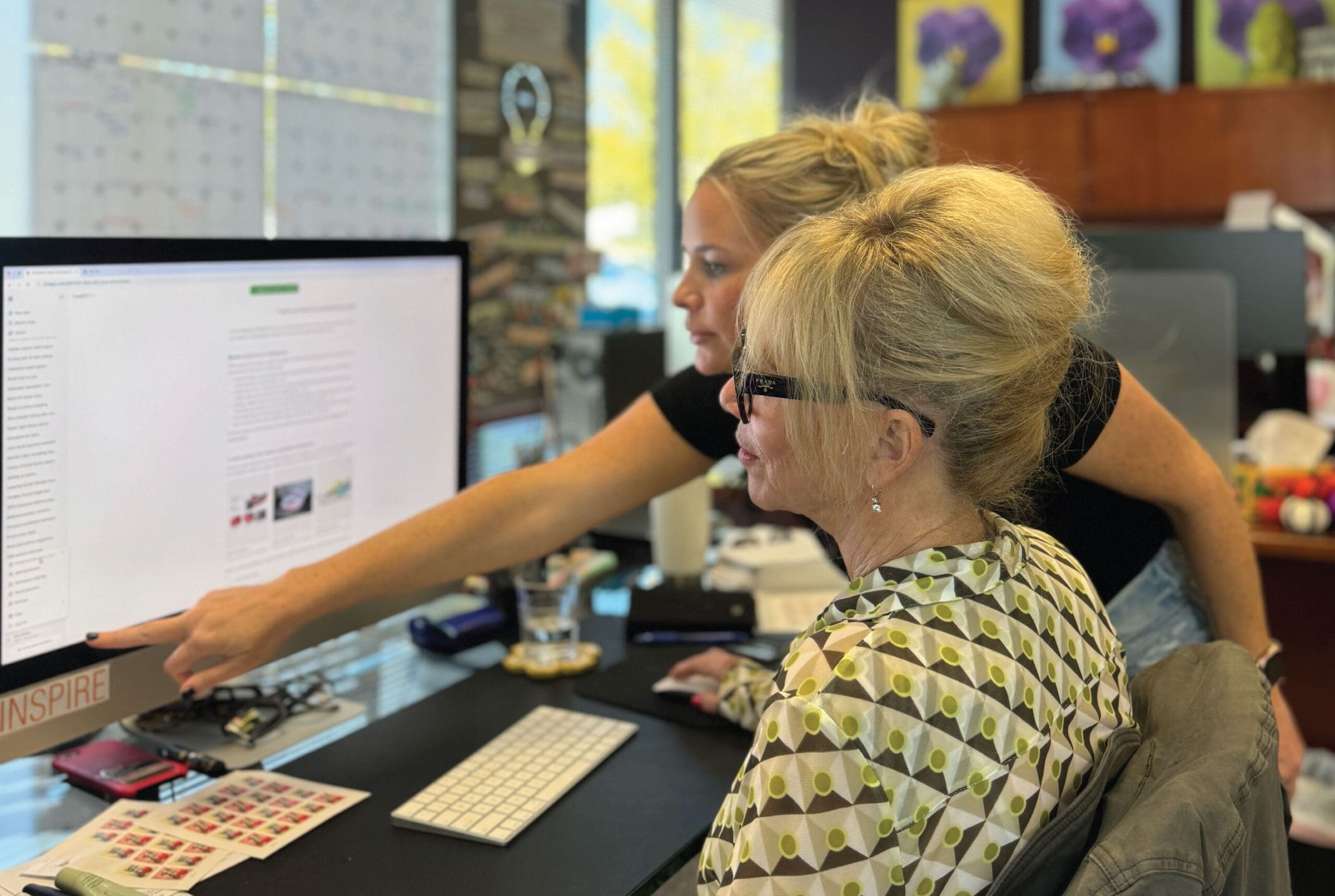 Chatbots and Checkouts: The Rise of AI-Powered Shopping This Holiday Season Kim Kelley and the Creative Marketing Arts team reviewing AI-powered shopping trends and chatbot marketing strategies on a computer.