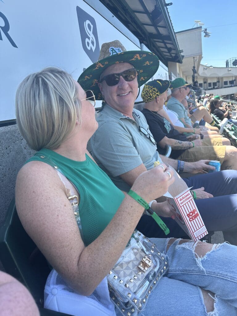 Grateful client outing at an A’s baseball game with two people enjoying the experience together.