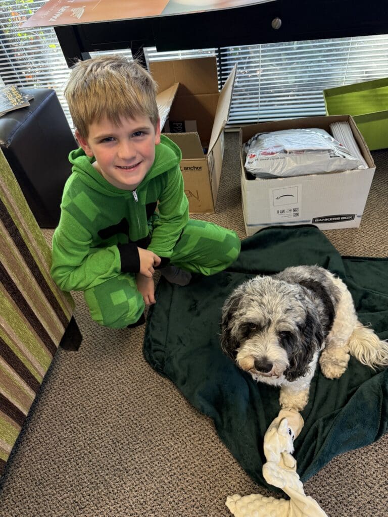 Kids and Dogs in Social Media Marketing Are the Secret Sauce for High Engagement Child sitting beside a dog on a green blanket creating a natural moment that reflects the power of kids and dogs in social media marketing.