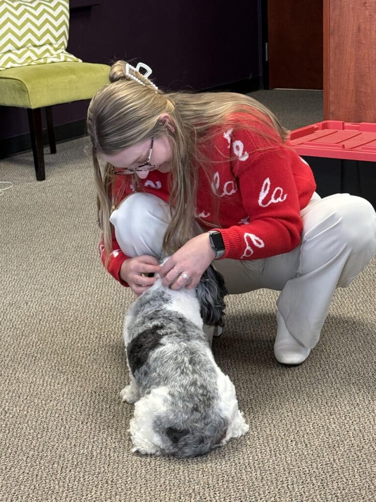 Kids and Dogs in Social Media Marketing Are the Secret Sauce for High Engagement Woman petting a dog in an office setting capturing a candid scene that supports the effectiveness of kids and dogs in social media marketing.