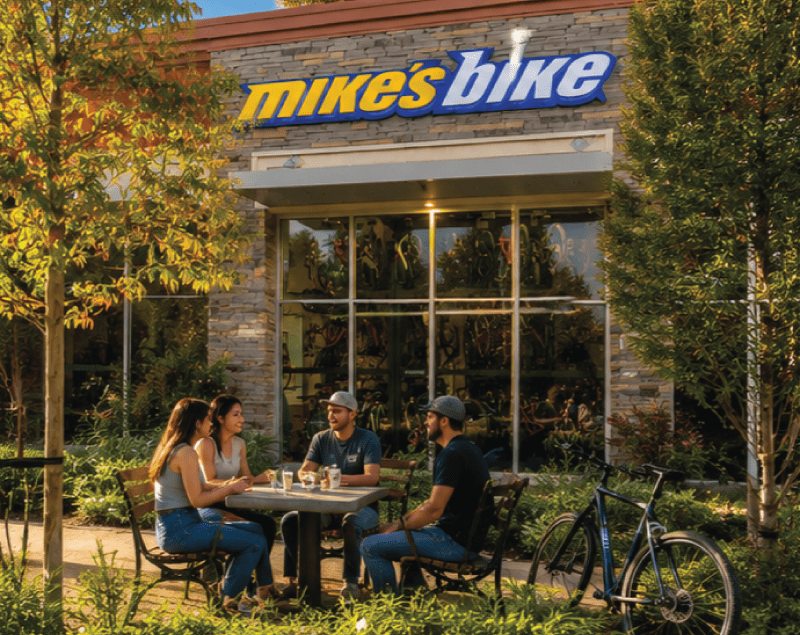 Market Research Photo of four people eating some food at a table in front of Mike's Bikes